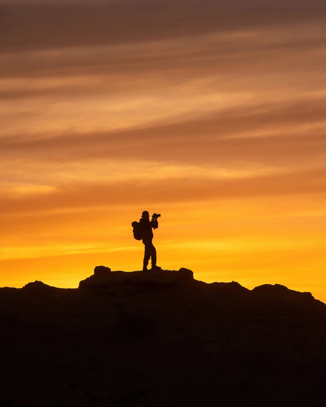 Silhouette of a man taking photos with a camera on a mountain