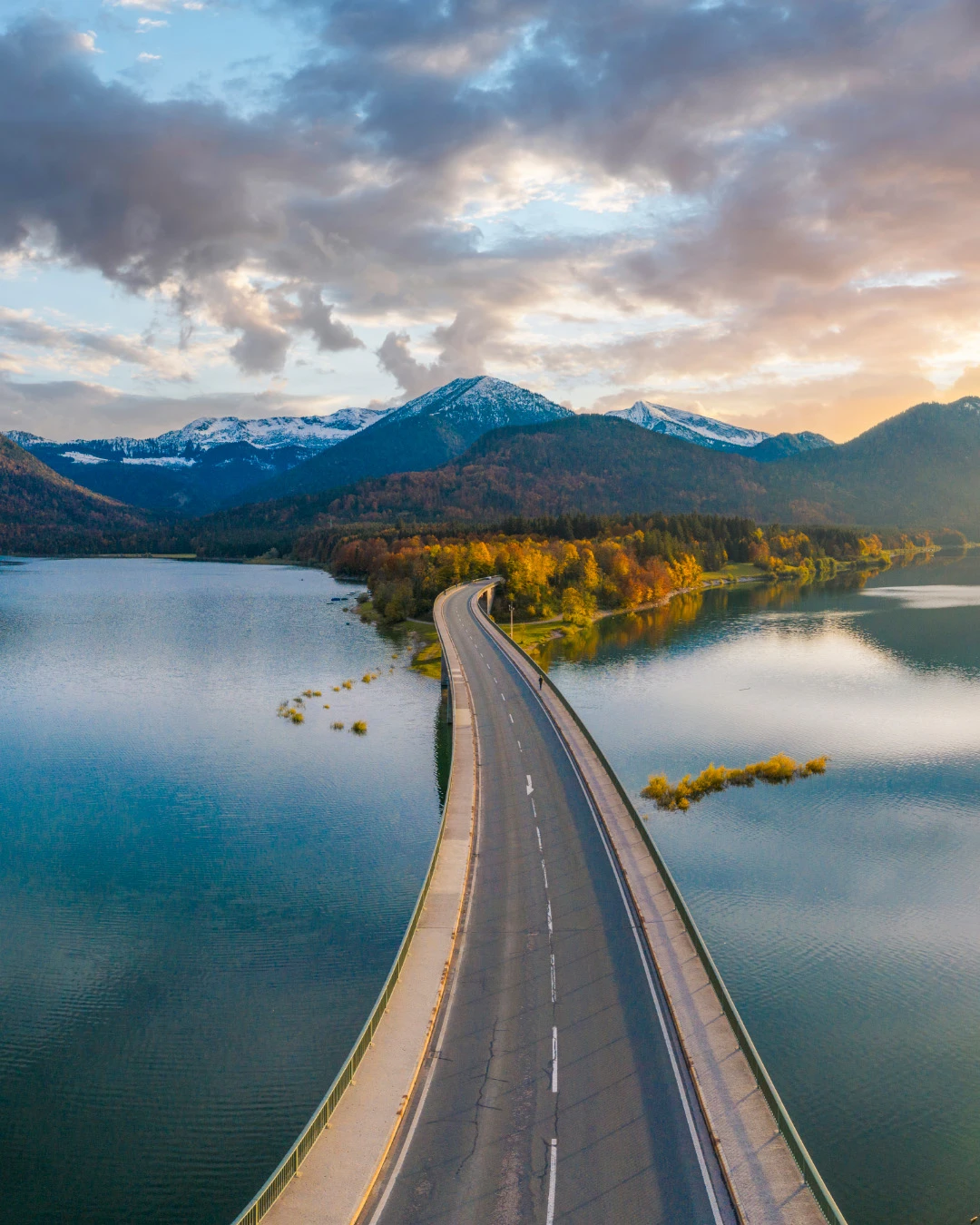 Road/bridge going over a lake with snowy mountains in the background